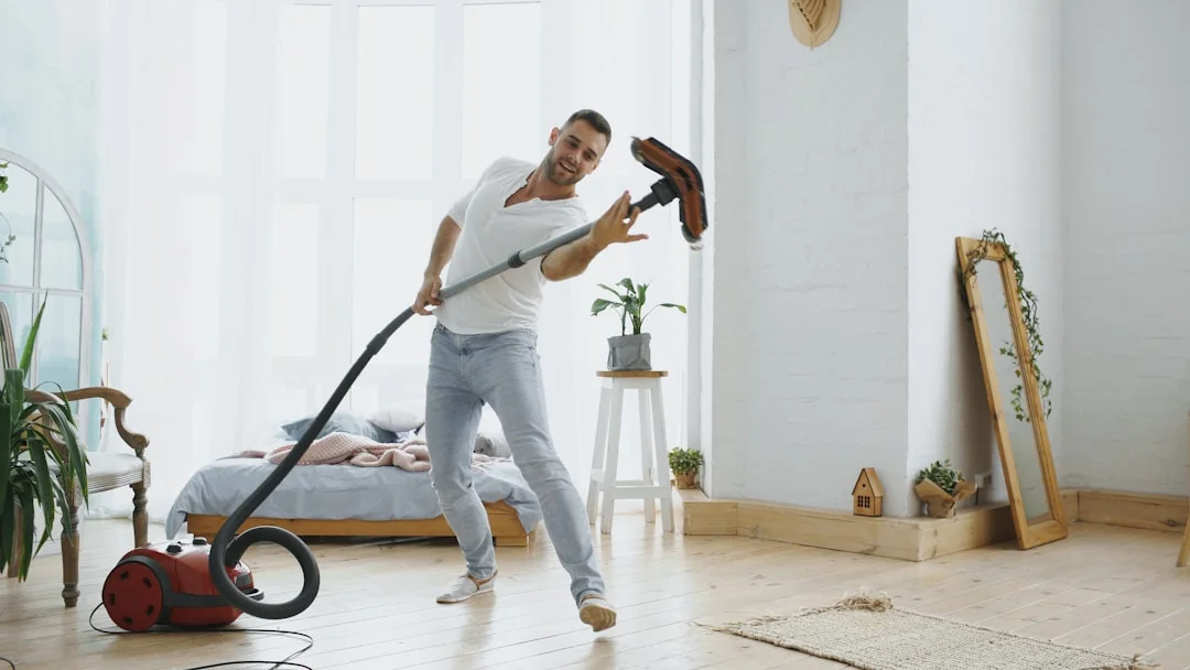 gallery-02 A professional cleaner in protective gear vacuuming the floor in a modern living room.